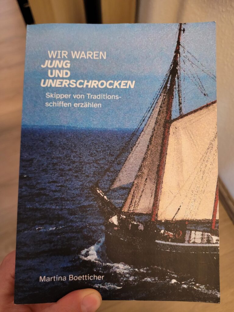 Das Cover von Wir waren jung und unerschrocken: Skipper von Traditionsschiffen erzählen von Martina Boetticher. Es zeigt ein augenscheinlich altes Photo eines Traditionsseglers, mit viel Film-Grain, auf See mit gesetzten Segeln.