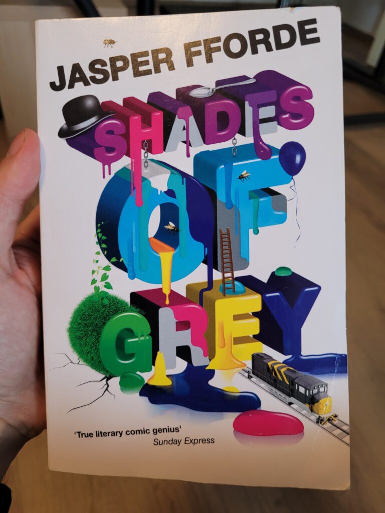 The cover of Shades of Grey, by Jasper Fforde. Essentially the title in big blocky 3D letters with goops of various colours on them and a bunch of doodads placed around.