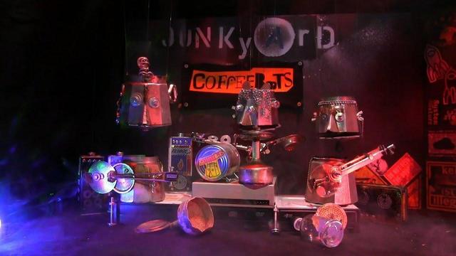The thumbnail of Never Mind the Gig Work… Here’s the Coffeebots! It shows part of the main characters, puppets made of upcycled Bialetti cans, performing as a band on stage.