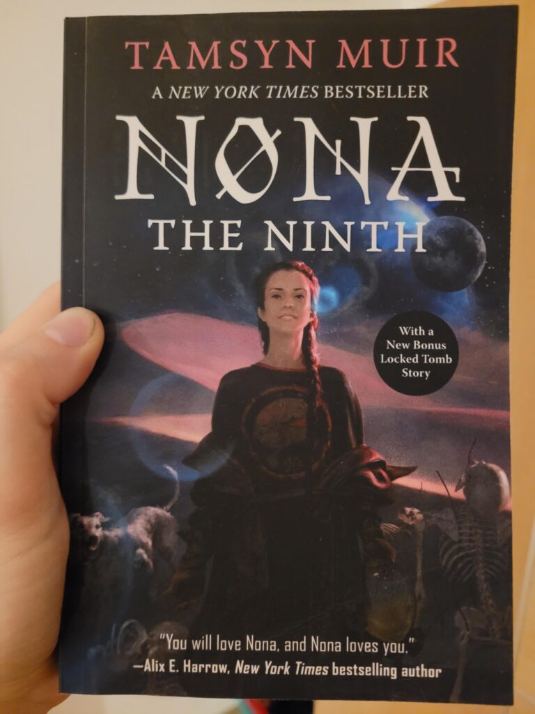 The cover of Nona The Ninth, by Tamsyn Muir It shows in front of a space-y background with a blue nebula and a planet or moon the titular character, a slim woman with long black hair and golden eyes. She wears a dark t-shirt with a print and an oversized jacket falling from her shoulders. Nona is framed on the left by the six-legged dog Noodle and on her right by a skeleton.